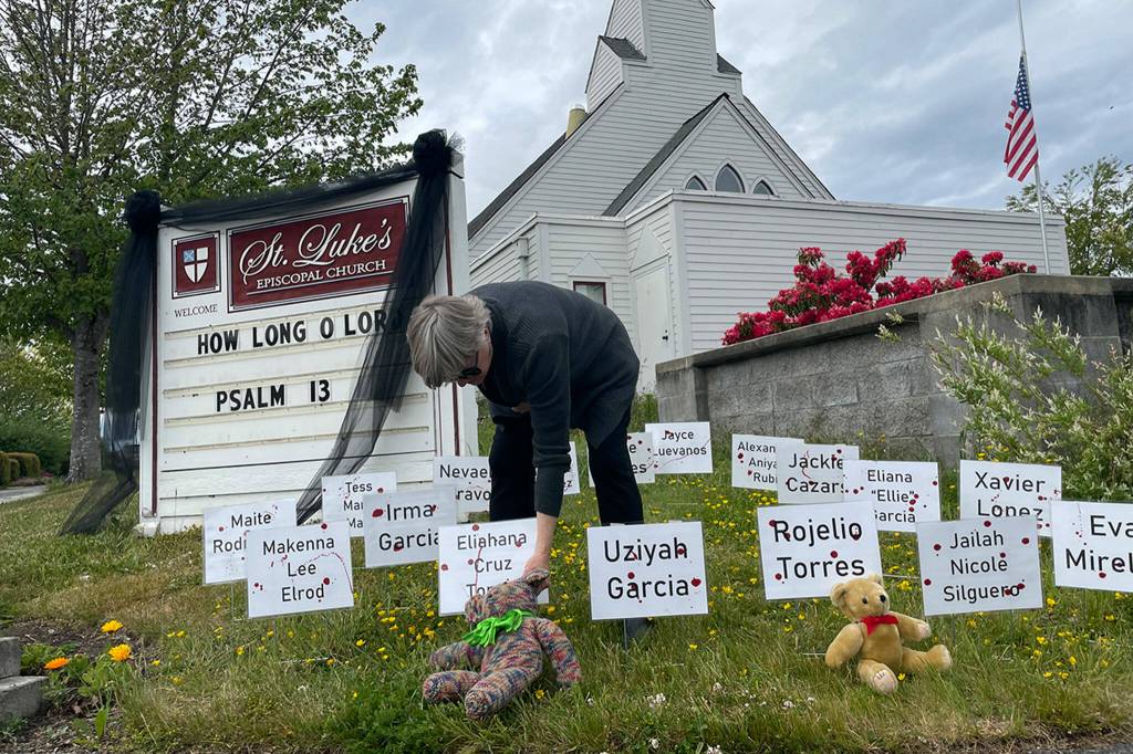 Rev. ClayOla Gitane, rector at St. Lukes Episcopal Church, places signs and bears to remember the victims of the May 24 shooting in Robb Elementary in Uvalde, Texas. More signs were being made inside and later placed to honor the victims.