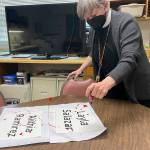 Sequim Gazette photo by Matthew Nash/ Rev. ClayOla Gitane, rector at St. Lukes Episcopal Church, spreads ink to symbolize the blood of two victims at the Uvalde, Texas school shooting. She displayed signs for the victims in front of the church.