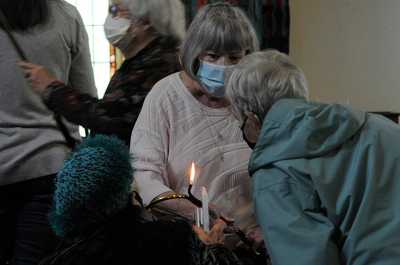 Sequim Gazette photo by Matthew Nash/ Pat Rublaitus helps light candles for a candlelight prayer service on May 27 inside St. Lukes Episcopal Church in Sequim for the victims of the Robb Elementary School shooting in Uvalde, Texas. About 40 people attended to pray and sing for the teachers and students and their families.