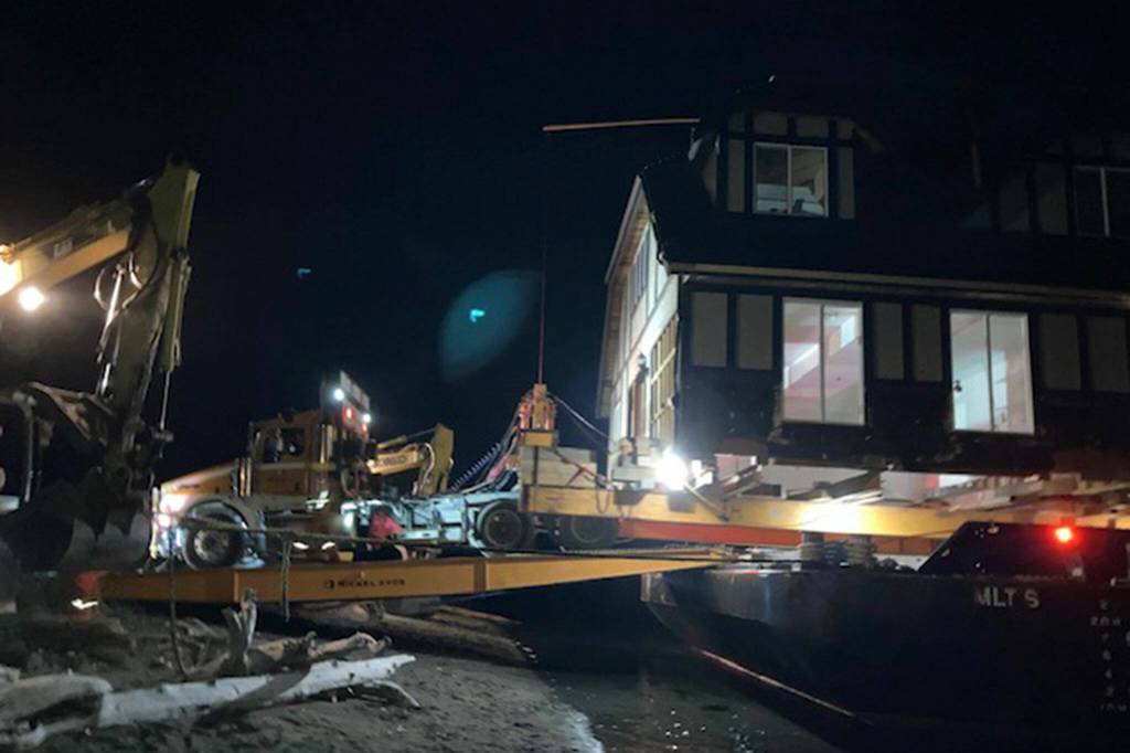 Photo courtesy of Lee Bowen/ Nickel Bros crew members begin to unload a 4,000-square-feet home from Surrey, British Columbia, on June 8. They had to wait for high tide around 11:30 p.m. to begin unloading.