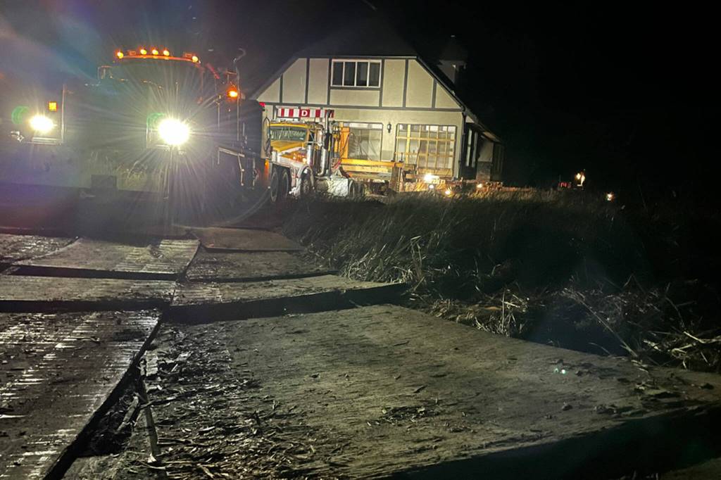 Sequim Gazette photo by Matthew Nash/ Hundreds of feet of plywood helped vehicles to travel along the shoreline in Dungeness so a new home could be delivered on June 8.
