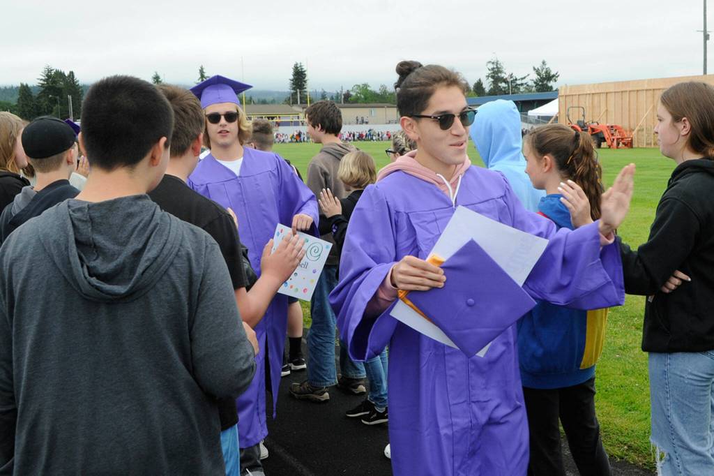 Sequim Gazette photo by Matthew Nash/ Sequim High seniors Harrison Bell, left, and Rafael Flores give high fives as they go through the 2022 Grad Walk.