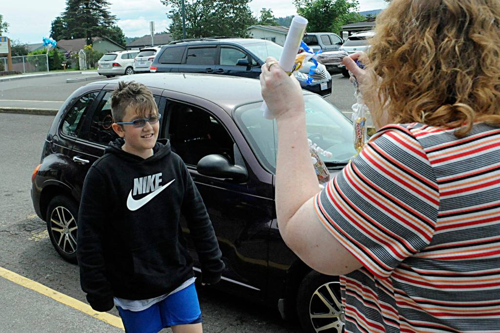 Sequim Gazette photo by Matthew Nash/ Helen Haller Elementary fifth grader Olyver Van Selus receives a candy lei and certificate from his teacher Saxon Holt on June 17. The school held a grad walk for its fifth graders earlier in the day and held a drive-through celebration for its fifth graders.