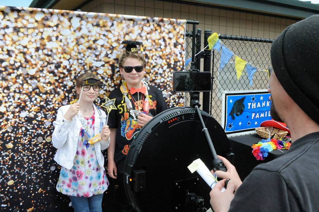 Piper Jackson and Alex Worth take a photo at the selfie booth as Pipers dad James snaps a pic too. The fifth graders participated in Helen Haller Elementarys drive-through event celebrating students moving up to middle school.