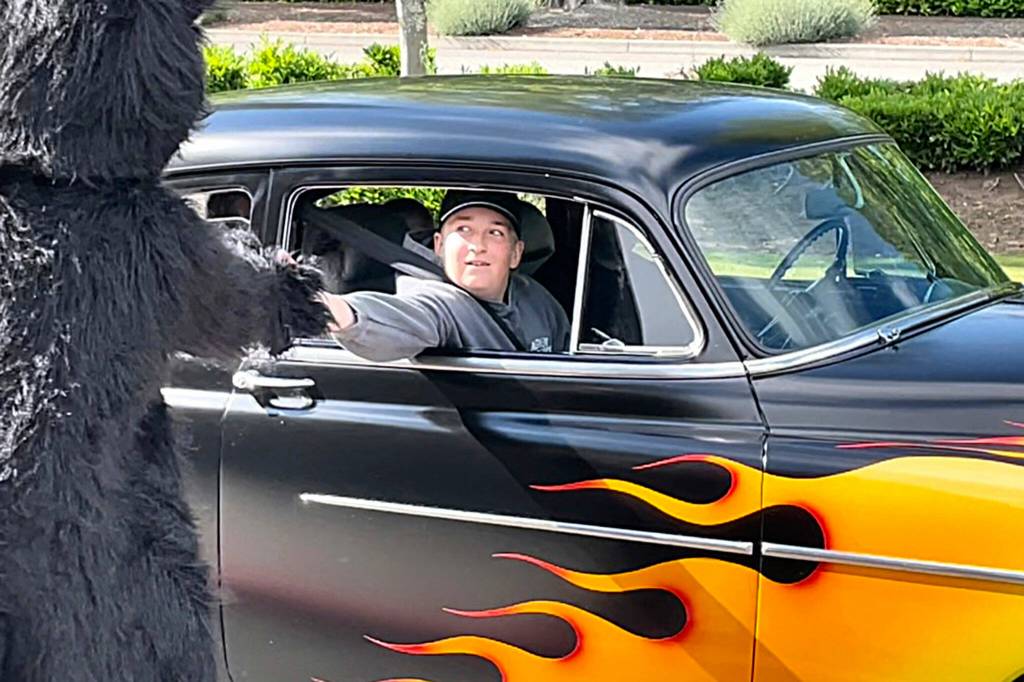 Sequim Gazette photo by Matthew Nash/ Eighth grader Rylee Gillaspy high fives Sequim Middle Schools Timberwolf during the schools drive-through celebration of students moving onto high school. Rylee rode in his dad Lucas 1949 Chevy Fleeting that he helped him work on.