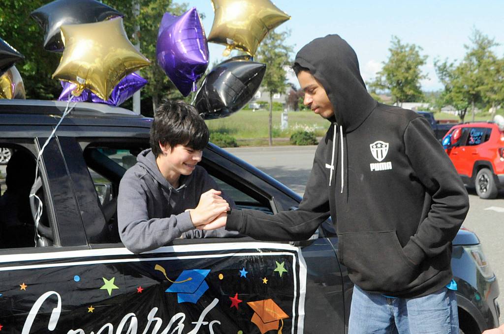 Sequim Gazette photo by Matthew Nash/ Zach Post high fives Clyde Baldassare as he goes through the Sequim Middle School drive-through event on June 16.