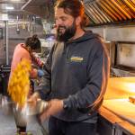 Caleb Messinger of the Southern Nibble tosses french fries to coat them evenly with salt. Sequim Gazette photo by Emily Matthiessen