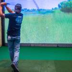 Sequim Gazette photo by Emily Matthiessen/ Derek Moore hits a real ball with a real club into the grass of a screen showing a simulated golf course at Sequims new golf club, Blade Brothers, an innovative operation run by friends with a love of the game. Moore is one of the founding members of the business, which opened in April at 10171 Old Olympic Highway.