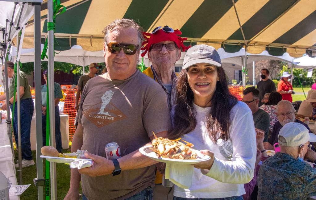 Sequim Gazette photo by Emily Matthiessen / John and Jessica Werle pause with plates of food at the Sequim Valley Lionss Crab Feed fundraiser in June. Elves Renfro, a past president of Sequim Valley Lions, grins behind them. We came to eat crab and meet the community, the Werles said.
