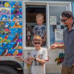 From left to right, Mr Orange and Justin, Charlie and Joe Parker pause inside and outside their ice cream truck in Sequim last Saturday. Northwest Treats has no fixed route, but travels all over Sequim and Port Angeles and in between and as far as Lake Sutherland and the lower Elwha. Joe Parker says that people message us to come by, using text, instagram and Facebook. Sequim Gazette photo by Emily Matthiessen