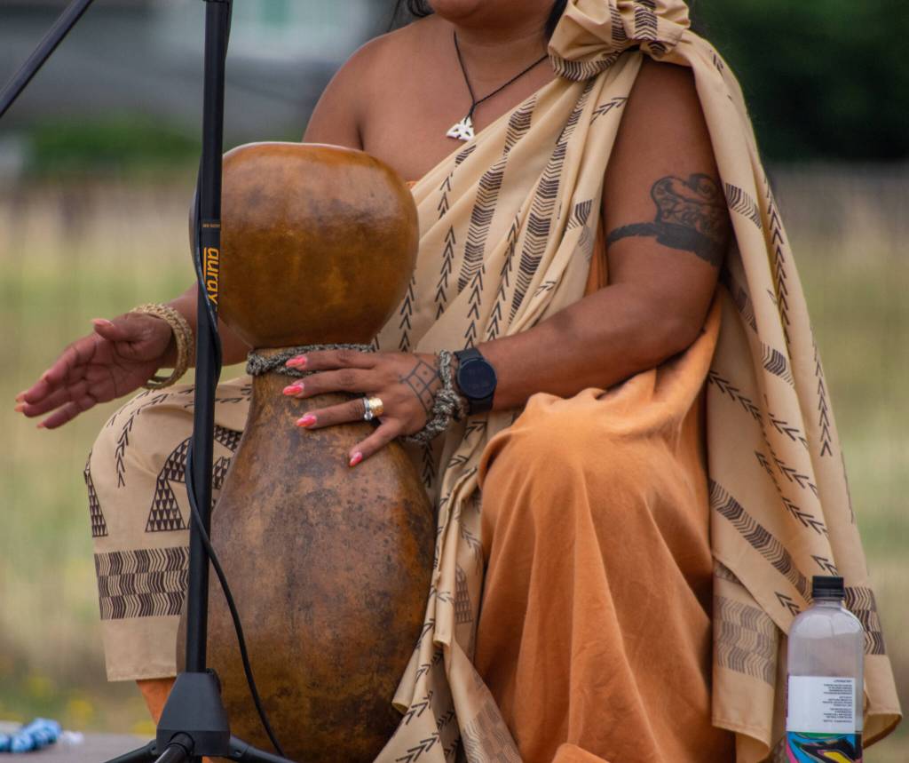 Sequim Gazette photo by Emily Matthiessen / An audience in the field behind the Sequim library on July 16 is treated to a talk covering many aspects of Hawaiian traditional culture and history, including details about the instrument called an Ipu by Candace Marie Kananiokamokihana Melendez, who began her formal training in hula at age 5. She and her daughter visited the libraries of the North Olympic Library system as part of their summer reading program.