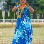 Sequim Gazette photo by Emily Matthiessen / Alakaʻi in training, Casara Desiree Hemakanamaikapu`uwai Caro leads members of a Sequim audience in a Hawaiian dance in the field behind the Sequim Library on July 16. Her mother, Candace Marie Kananiokamokihana Melendez of Hālau Hula Ka Lei Mokihana I Ka Ua Noe, plays the ukulele on the stage. North Olympic Library System hosted the dance, history and language workshop as part of their summer reading program.