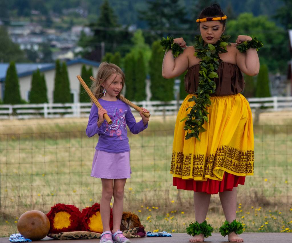 Sequim Gazette photo by Emily Matthiessen
Alakai Makana Caro of Halau Hula Ka Lei Mokihana I Ka Ua Noe, shows Skye Kading, 7, how to use the Kalaau, a traditional instrument used in hula performances, during a workshop in Sequim on July 16, courtesy of the North Olympic Library System. Kading said she liked the experience.