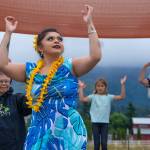 Alakaʻi in training, Casara Desiree Hemakanamaikapu`uwai Caro leads members of a Sequim audience on Saturday in a Hawaiian dance in the field behind the Sequim library. Her mother, Candace Marie Kananiokamokihana Melendez of Hālau Hula Ka Lei Mokihana I Ka Ua Noe, plays the ukulele on the stage. North Olympic Library System hosted the dance, history and language workshop as part of their summer reading program. Sequim Gazette photograph by Emily Matthiessen