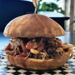 Photo courtesy of Belles Black Pot Coffee / An example of the house-smoked meat sandwiches available at Belles Black Pot at 131 River Road in Sequim, owned and operated by the Owen family: smoked pork, house sauce, crispy onions on a garlic buttered pub bun.