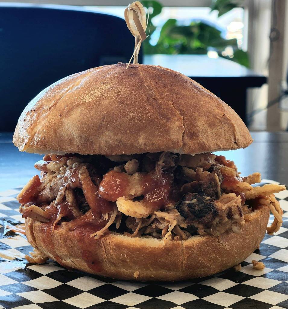 Photo courtesy of Belles Black Pot Coffee / An example of the house-smoked meat sandwiches available at Belles Black Pot at 131 River Road in Sequim, owned and operated by the Owen family: smoked pork, house sauce, crispy onions on a garlic buttered pub bun.