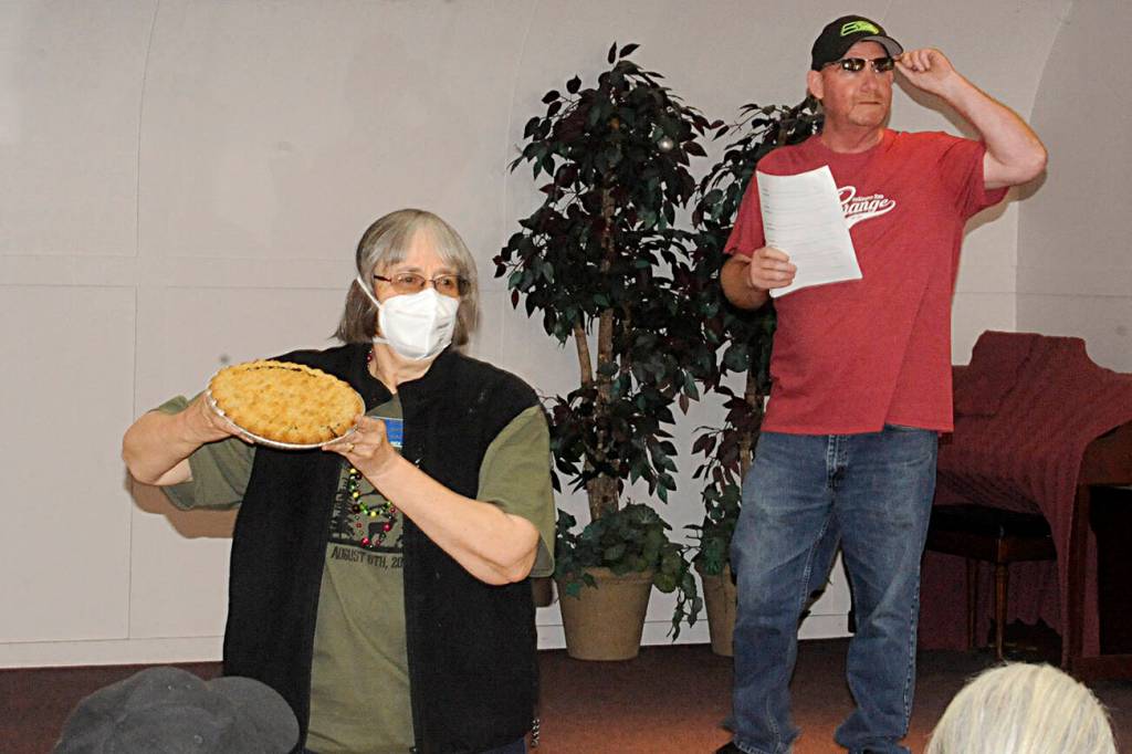 Sequim Gazette photo by Matthew Nash/ Judy Moilanen with Crescent Grange holds up a marionberry pie made for bidding as Dave McDaniels, president of Sequim Prairie Grange, looks for bidders on July 23 at the All-Grange Dessert Auction.
