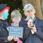 Florence and Michael Bucierka, on left and right, accept a plaque from Vicki Sensiba, center, on Oct. 10 that names the Olympic Unitarian Universalist Fellowships Little Free Pantry expansion/Social Justice Building after them for their efforts to help develop it. Sequim Gazette photo by Matthew Nash