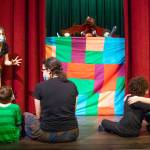 Roxy Woods, a wizard/storyteller, entertains a small hobbit crowd in the first scene of Olympic Theatre Arts upcoming production, The Hobbit. The puppet show mirrors latter scenes in which giant puppets interact with the cast. From left to right: Woods, Wally McCarter (Hobbit Child), Amber McCarter (Hobbit Mother), Egan Owie (Hobbit Child), Chloe Loucks (Hobbit Mother). The hand puppets were created by Curt White. Sequim Gazette photo by Emily Matthiessen