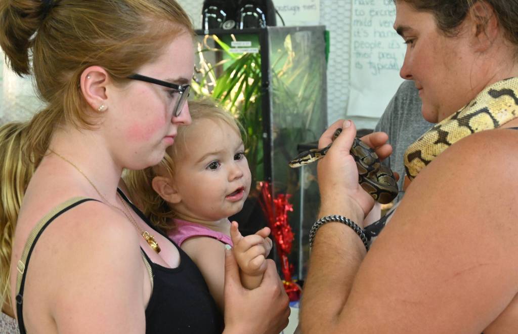 From left, Haley Petty and Payton Berry check out a snake held by Agnews Crystal Berry at the Clallam County Fair on Aug. 18.