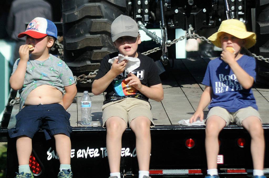 Photo by Keith Thorpe/Olympic Peninsula News Group / Siblings, from left, Charlie Jones, 4, Samuel Jones, 8, and August Jones, 6, all of Port Angeles, eat fresh scones on Aug. 18 at the Clallam County Fair.