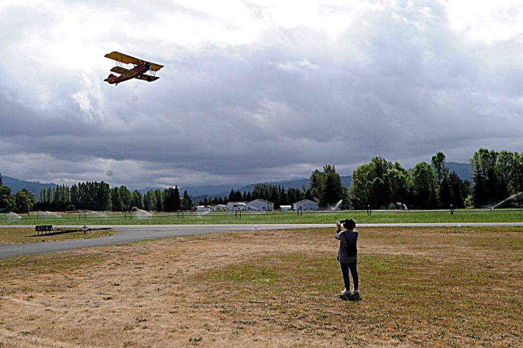 Sequim Gazette photo by Matthew Nash/ A wife videos her husband flying in a 1929 Travel Air Plane flown by Keith Kossuth on Aug. 27 at the Air Affaire.