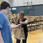 Amala Kuster with the Sequim Sunrise Rotary hands off a bag to James Joseph Dorrell, 14, with the Boys & Girls Club, during the Back to School Fair.