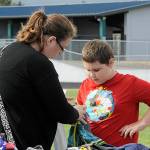 Sequim Gazette photo by Matthew Nash/ Crystal Jones sizes up some clothes for her son Titus, 9, a fourth grader, at the Back to School Fair on Aug. 27 on the Sequim School Districts Athletic Field.
