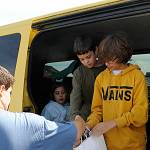 Sequim Gazette photos by Matthew Nash
Above: Sequim Middle School principal Mark Harris talks with new middle schooler and incoming sixth grader Iylie James-Lundgren at the Back to School Fair as her mom Holly Atwood listens in. 
At left: Volunteer Kim Rosales hands a backpack to a car as part of the Back to School Fair on Aug. 27.