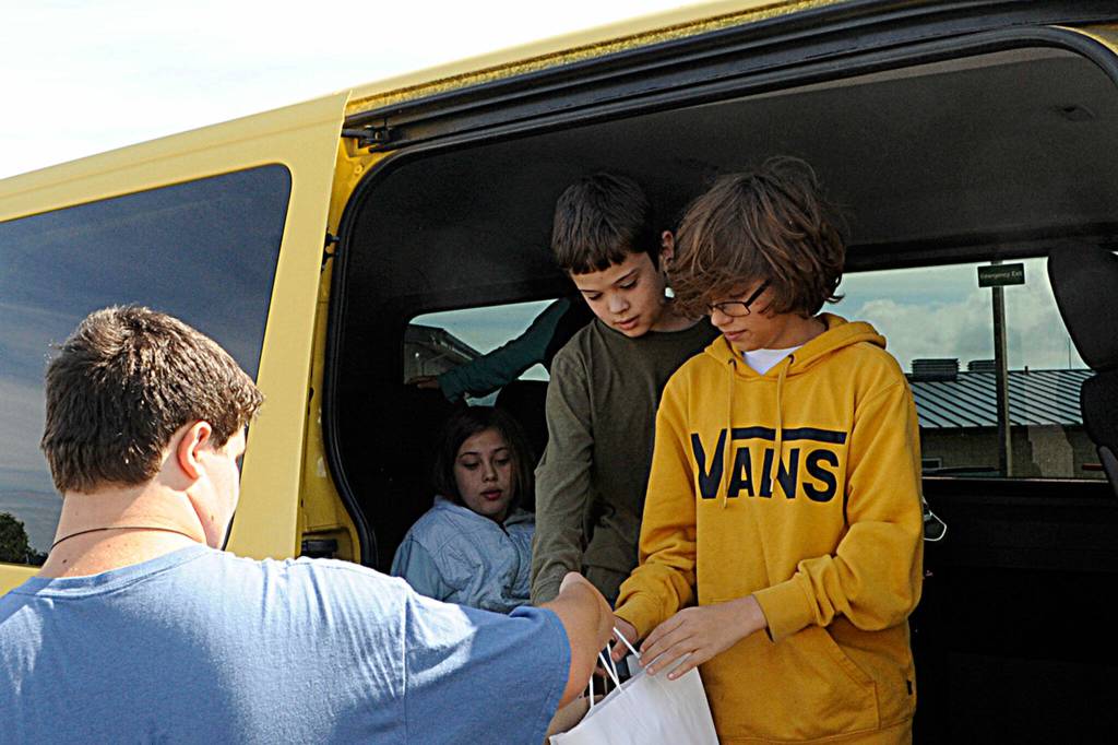 Sequim Gazette photos by Matthew Nash
Above: Sequim Middle School principal Mark Harris talks with new middle schooler and incoming sixth grader Iylie James-Lundgren at the Back to School Fair as her mom Holly Atwood listens in. 
At left: Volunteer Kim Rosales hands a backpack to a car as part of the Back to School Fair on Aug. 27.