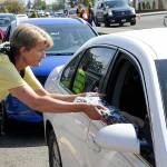Sequim Gazette photo by Matthew Nash/ Volunteer Kim Rosales hands a backpack to a car as part of the Back to School Fair on Aug. 27.