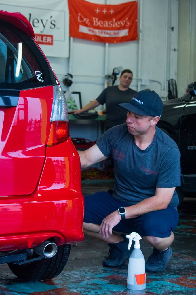 Sequim Gazette photo by Emily Matthiessen / Christopher Burris works on a car while his sister Kim Burris looks on in the background.