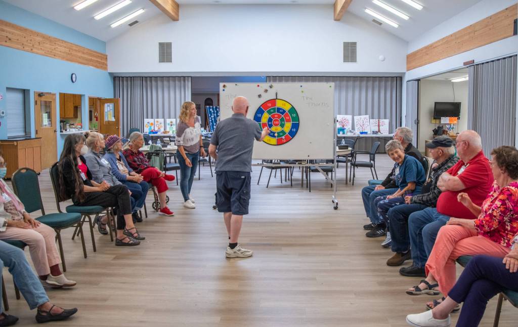 Sequim Gazette photo by Emily Matthiessen / Volunteers and people living with memory loss play a two-team game in which they take turns throwing a number of small velcro balls into a dart board during a Tims Place gathering at Trinity United Methodist Church in Sequim.