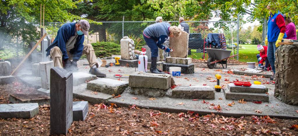 Sequim Gazette file photo by Emily Matthiessen/ Volunteers work to improve the memorial corner created by Sequim Prairie Garden Club members in the 1960s at Pioneer Memorial Park in 2021. The history of the Garden Club and the park are intertwined, and from the beginning the club has cared for this 4 acre former cemetery with the aid of community members, turning it into the lush park off Washington Street that all residents and visitors can enjoy. The headstones in the memorial corner were fenced in the early 1980s due to vandalism that occurred through the years. Current members of the club requested that anyone in the community who may have a piece of one of the stones to please return it so they can piece together more of the headstones.