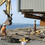 Sequim Gazette photo by Matthew Nash/ Crew men with Nickel Bros look to make sure a Dungeness home stays on track for a safe move 100 feet away from the hillside.