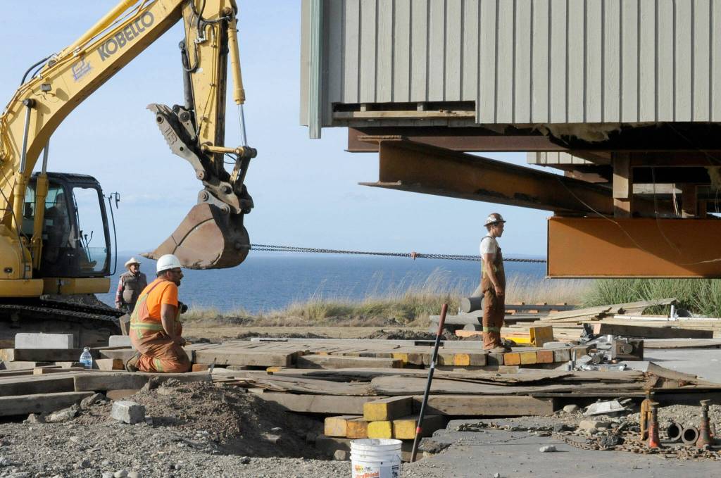 Sequim Gazette photo by Matthew Nash/ Crew men with Nickel Bros look to make sure a Dungeness home stays on track for a safe move 100 feet away from the hillside.