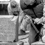 Sequim Gazette photo by Emily Matthiessen / Using a chisel and hammer, Chris Smith chips away white mortar from the headstone of the infant son of R. and Eleanor Irwin, in the corner of Pioneer Memorial Park. The photo, Gone by not forgotten, earned Emily Matthiessen a third place in the/W Feature, Portrait or Pictorial Photo division in the Washington Newspaper Publishers Associations 2022 Better Newspaper Contest.