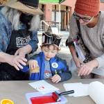 Kaine Lamb, 4, makes an ink print with the assistance of his mother, Carlie Lamb of Port Angeles, right, and Jan Dove of the Port Angeles Fine Arts Center. Print-making was a featured children's event during Saturday's Peninsula College Fall Spectacular on the school's Port Angeles campus. The event, hosted by the school to bring the community to the campus, also featured displays and demonstrations, tethered balloon rides, food and music. (Keith Thorpe/Peninsula Daily News)