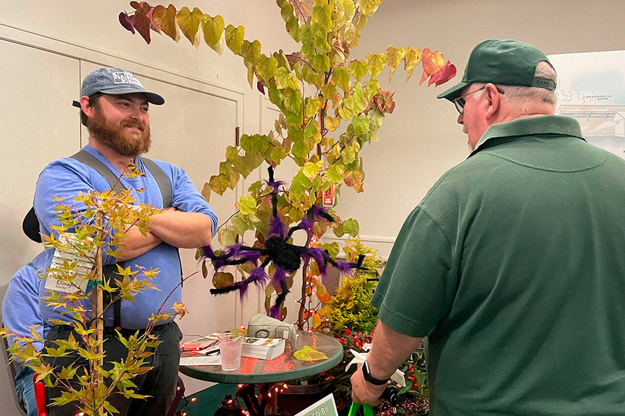 Sequim Gazette photo by Matthew Nash/ Stew Cockburn, foreman at New Dungeness Nursery, talks with Charles Norman of WeDo Fudge, from the nurserys stand at the Business Showcase at Sunlands clubhouse. The nursery was one of 30-plus vendors to participate.