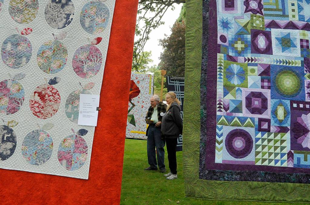 Sequim Gazette photo by Matthew Nash/ Carolyn and Alan Jones of Diamond Point visit the Sunbonnet Sue Quilt Clubs outside show on July 16 in Pioneer Memorial Park. We came every year (before COVID-19) and I love (the park). I love the openness, Carolyn said.
