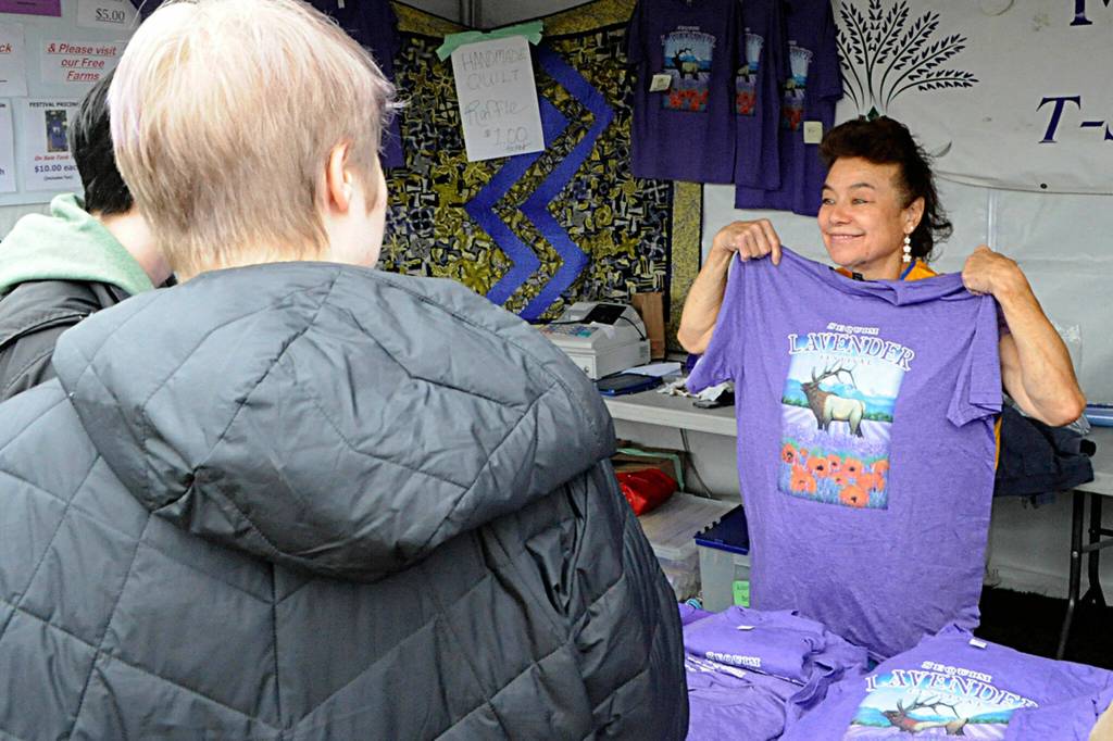 Sequim Gazette photo by Matthew Nash/ June Nicholas with the Sequim Valley Lions shows the design for the Sequim Lavender Festival T-shirt for patrons at the Street Fair on July 16.