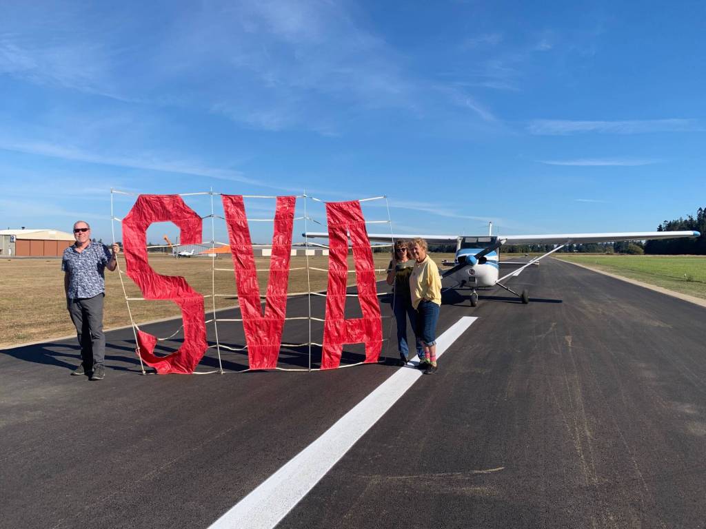 Submitted photo / Sequim Valley Airport owners Andy and Jane Sallee and Emily Westcott on Oct. 5 celebrate the completion of a project to rehabilitate, pave and restripe the airport runway.