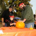Sequim Gazette photo by Matthew Nash/ Six-year-old ninja Aiden Havel-Beristain carves a pumpkin with his ninja parents Gabriela Beristain-Havel and Tim Havel at the Sequim Prairie Granges Trunk-or-Treat on Oct. 29. For Halloween, Aiden said he loves Kit-Kats.