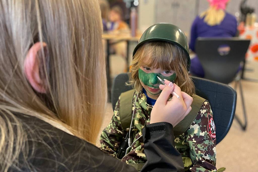 Sequim Gazette photo by Matthew Nash/ Sequim High cheerleader Grace Minty, 14, paints camouflage on five-year-old Peyton Winters face during Haunted Hallways on Oct. 29.