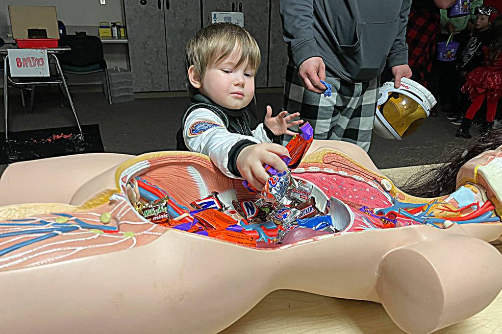 Sequim Gazette photo by Matthew Nash/ Spaceman Tucker Weatherly, 4, enjoys some treats from a dummys tummy inside during Sequim High Schools Haunted Hallways event on Oct. 29. The HOSA club, now known as Future Health Professionals, offered gloves for children to wear and touch brains, and other body parts.