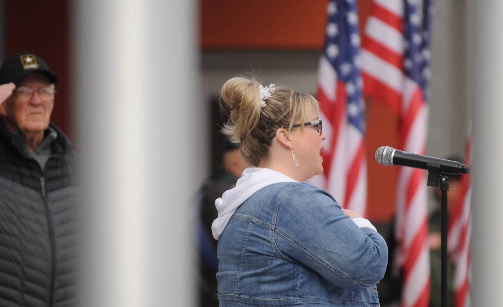 Sequim Gazette photo by Michael Dashiell / With Tom Coonelly (U.S. Army, ret.) looking on Amanda Bacon sings the National Anthem at Friday mornings Veterans Day Ceremony, held at the Sequim Civic Center plaza near downtown Sequim.