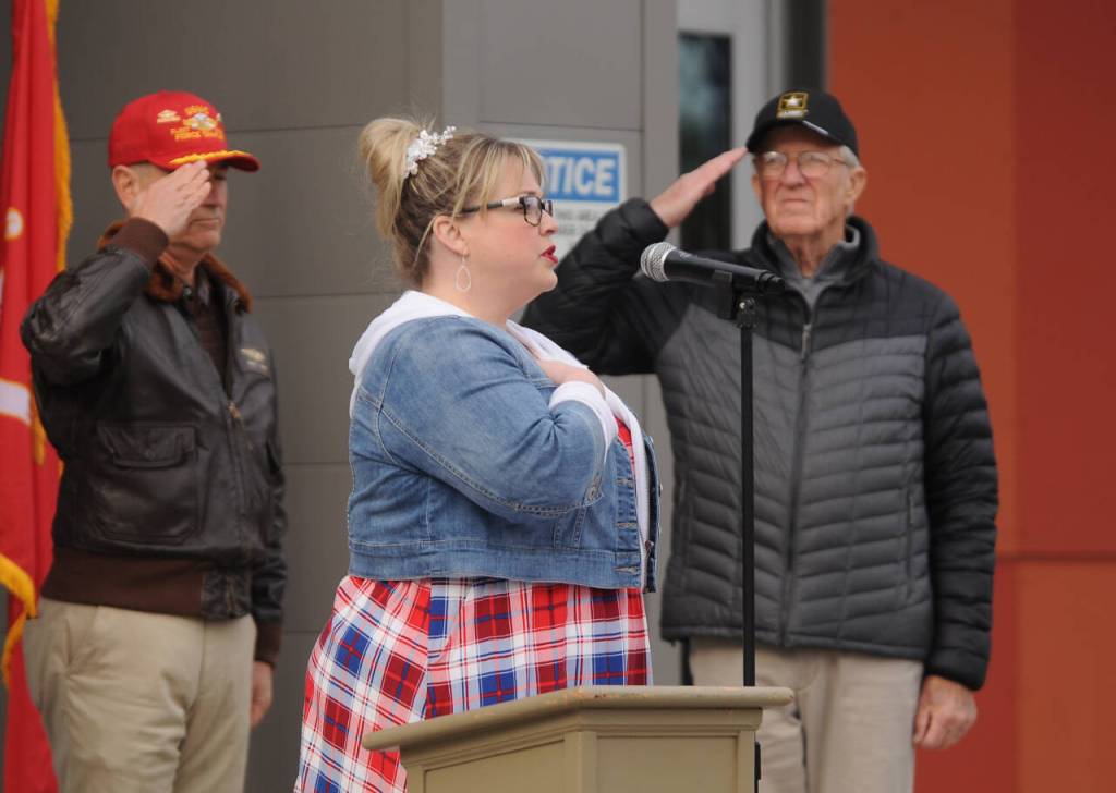 Sequim Gazette photo by Michael Dashiell / With chaplain Cpt. Mike Hakanson (U.S. Navy, ret.), left, and Tom Coonelly (U.S. Army, ret.) looking on, Amanda Bacon sings the National Anthem at Friday mornings Veterans Day Ceremony, held at the Sequim Civic Center plaza near downtown Sequim.