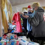 Matthew Nash/Sequim Gazette file photo
Kathy Joyner, co-organizer of Toys for Sequim Kids, helps Jean Ann Houk size up a t-shirt for one of her children at the 2021 event in Sequim Prairie Grange. This years event is set for 10 a.m.-6 p.m. Dec. 14.