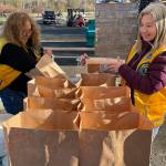 Sequim Gazette photo by Matthew Nash/ Denice Irish, on left Lou Ann Linder with the Sequim Valley Lions bag bread and other items for the Family Holiday Food Bag Distribution day on Nov. 18 in Carrie Blake Community Park.
