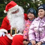 Sequim Gazette photo by Michael Dashiell / In middle, Liv Hanson, 8, and Zoey Hanson, 9, both of Sequim, talk with Santa Claus (Stephen Rosales) at the Hometown Holidays event Saturday afternoon in downtown Sequim.